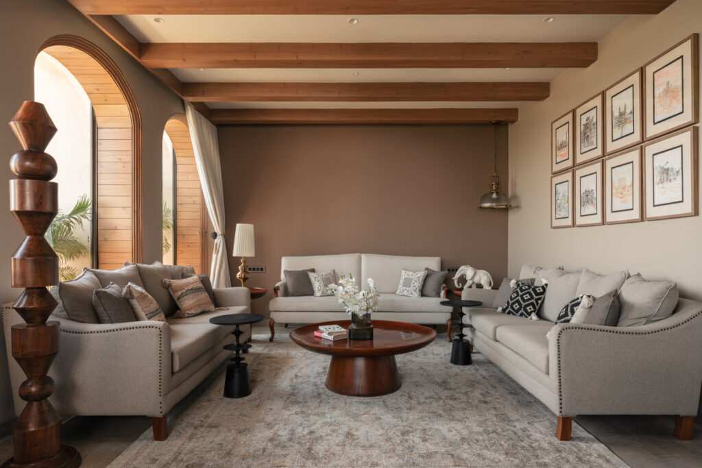 Wide view of the Still-Wood living room with upholstered sofas, timber ceiling beams and a wall of framed artwork.