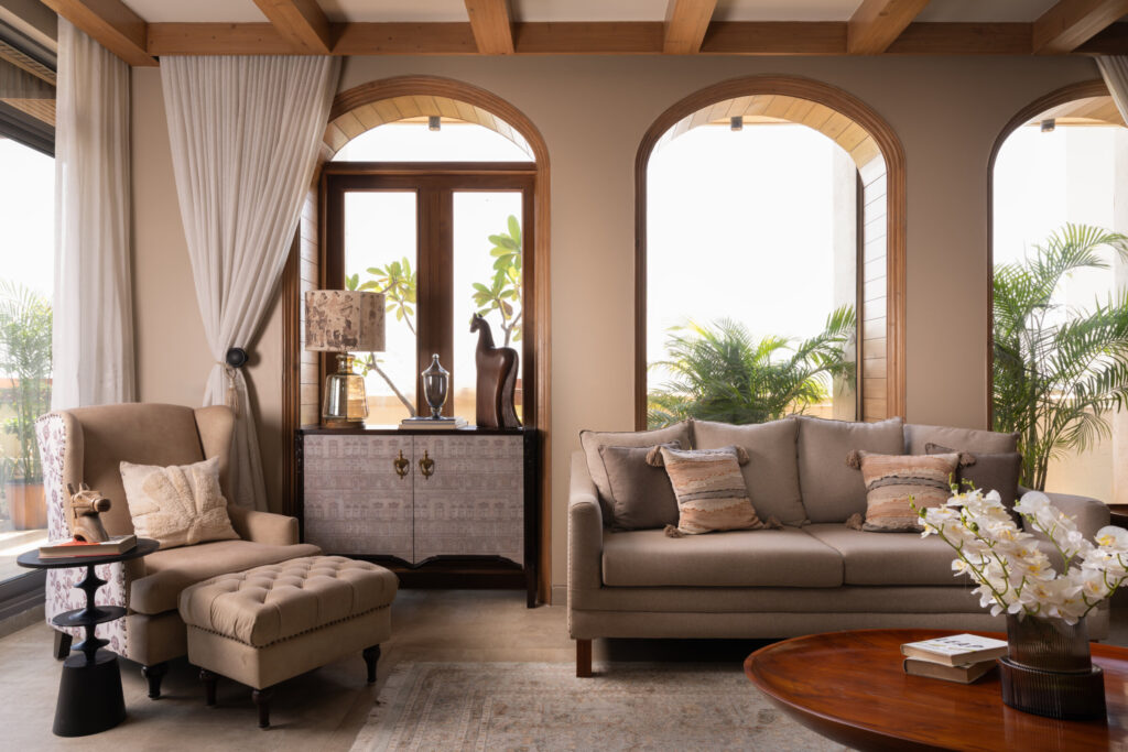 Upholstered lounge seating arranged in front of arched windows overlooking terrace planting at Still-Wood.
