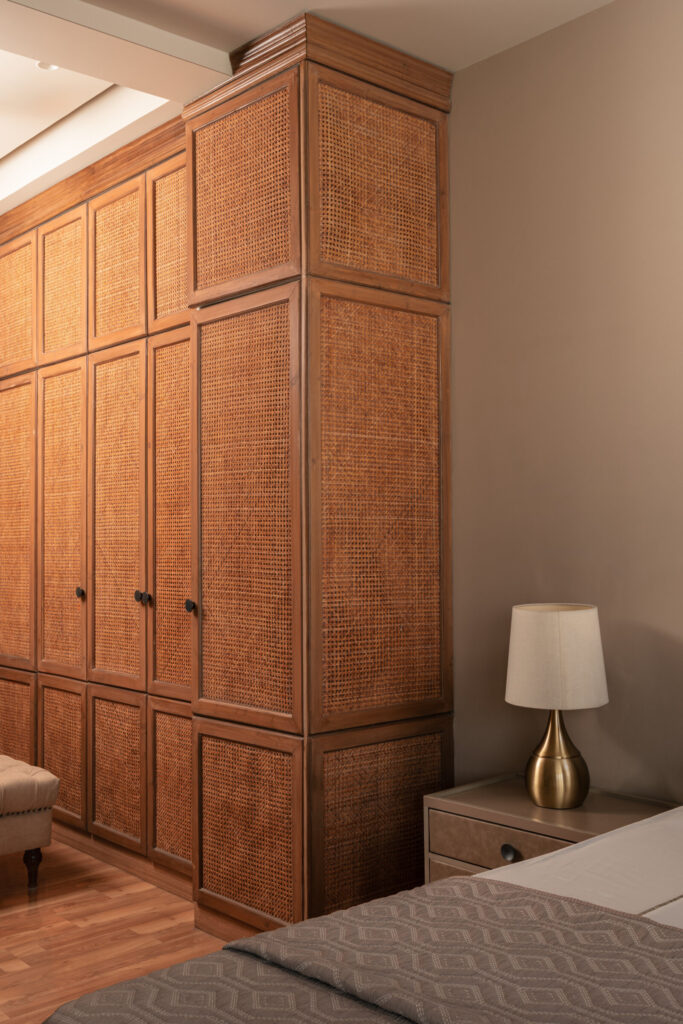 Tall paneled timber wardrobes beside a bedside table and pale lamp in the Still-Wood bedroom.